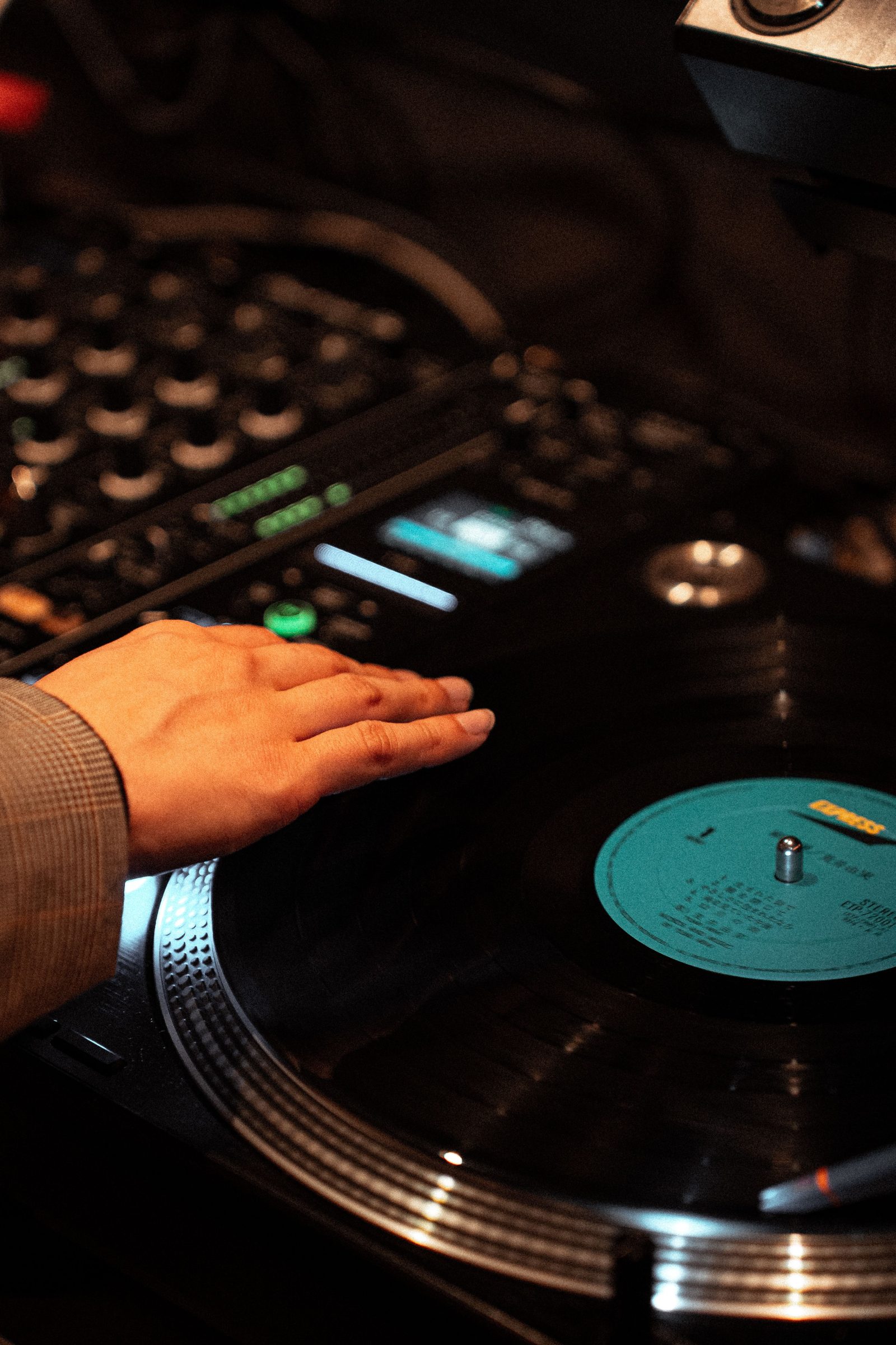 A DJ's hand spinning a vinyl record on a turntable in a dimly lit club