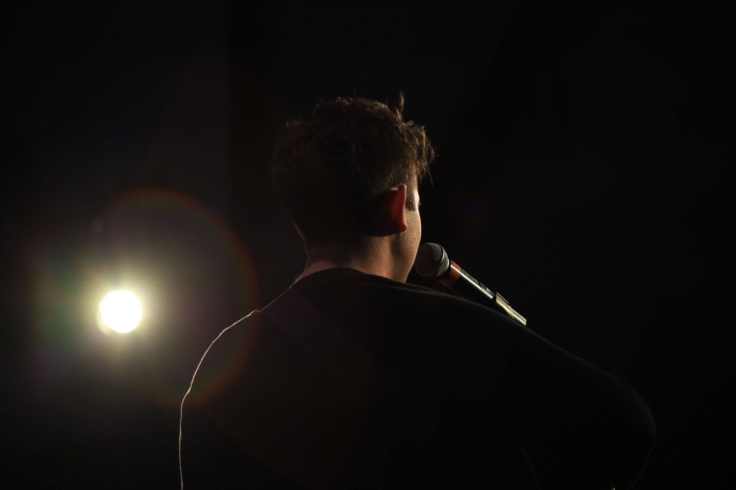 A singer on stage in silhouette, lit by a single spotlight