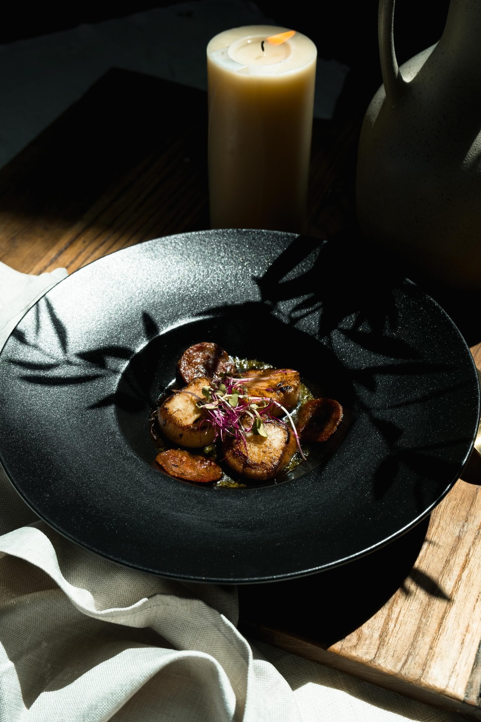 A plated dish on a dark ceramic plate under low light