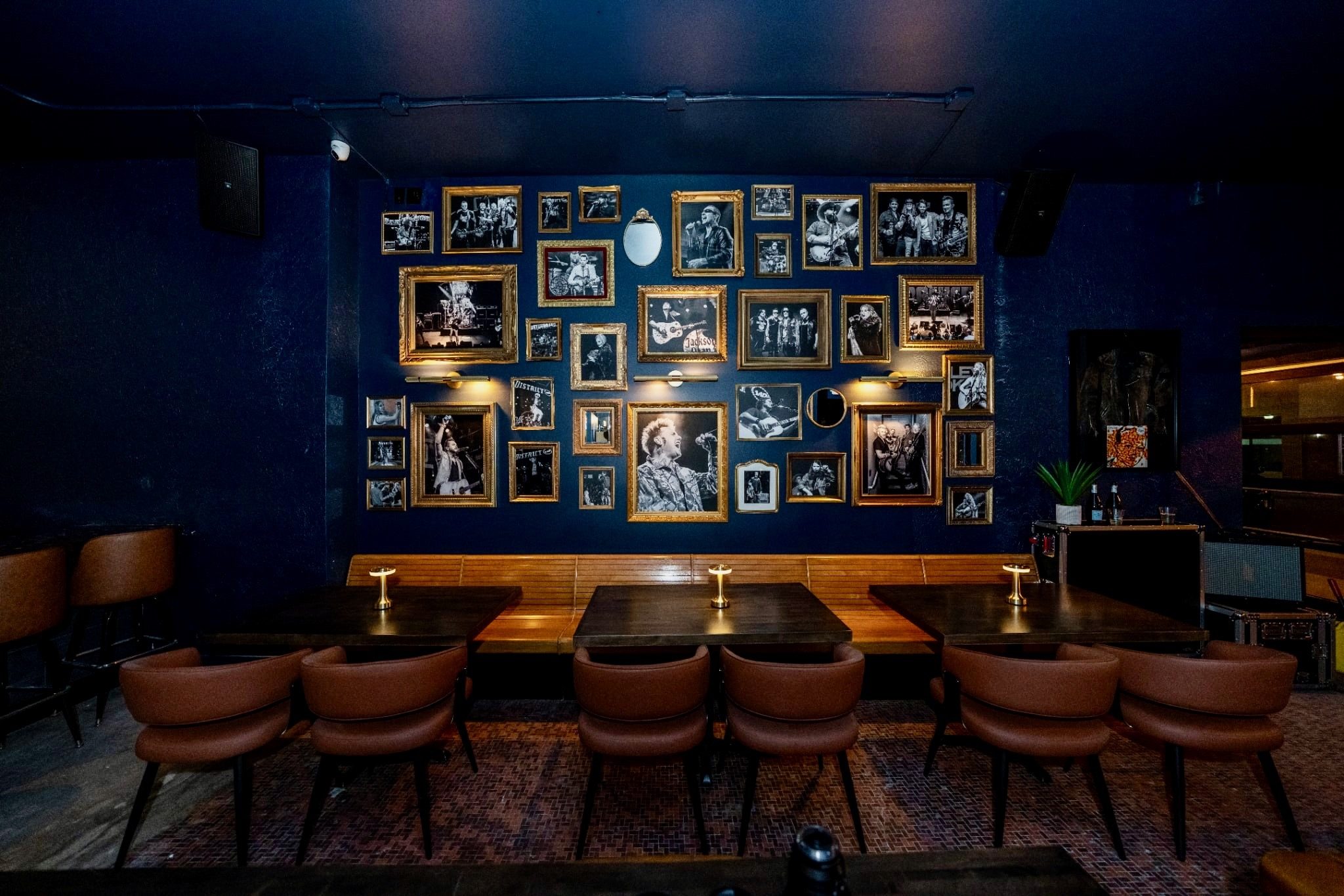 A wall of gold-framed black-and-white photos of District 142 performers above a wooden banquette